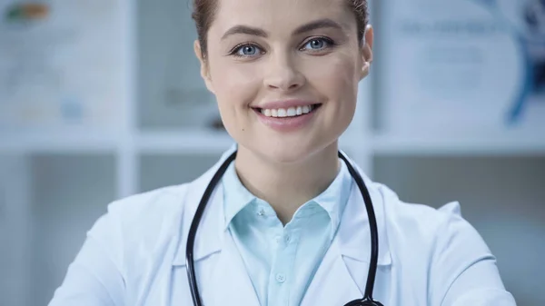 Cheerful doctor in white coat smiling and looking at camera — стоковое фото