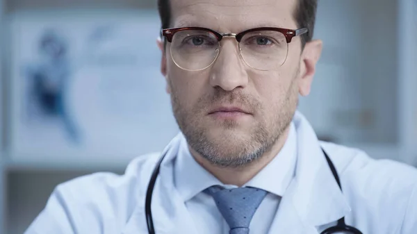 Confident doctor in glasses and white coat looking at camera in clinic — Photo de stock