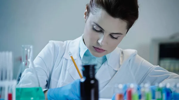 Pretty scientist writing down result of analysis in laboratory — Stock Photo