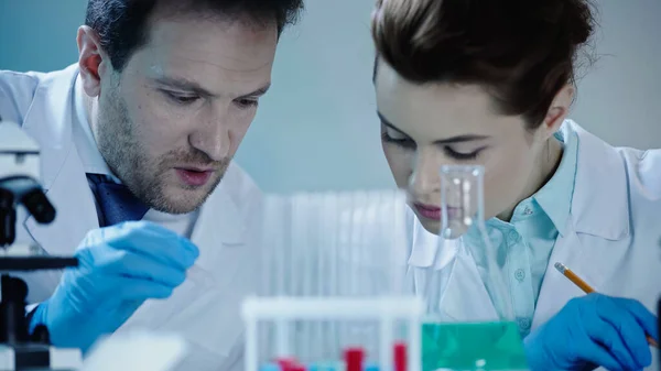 Two scientists in latex gloves and white coats looking down in laboratory — Fotografia de Stock