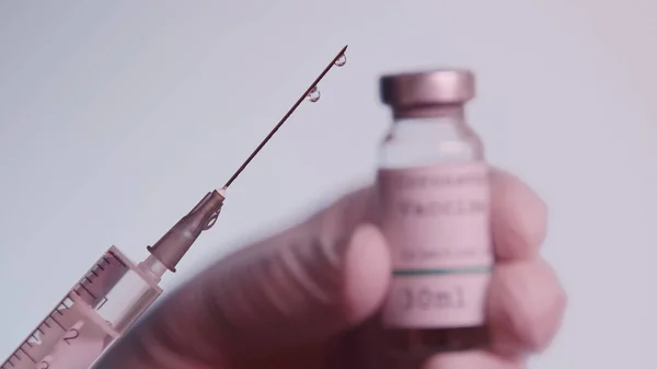 Cropped view of scientist holding syringe and blurred bottle with vaccine isolated on grey — Foto stock