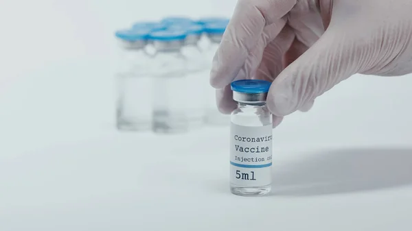 Cropped view of person holding bottle with coronavirus vaccine liquid on white — Foto stock