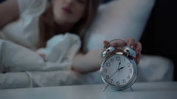 Cropped view of blurred woman turning off alarm clock in bedroom at night — Stock Photo