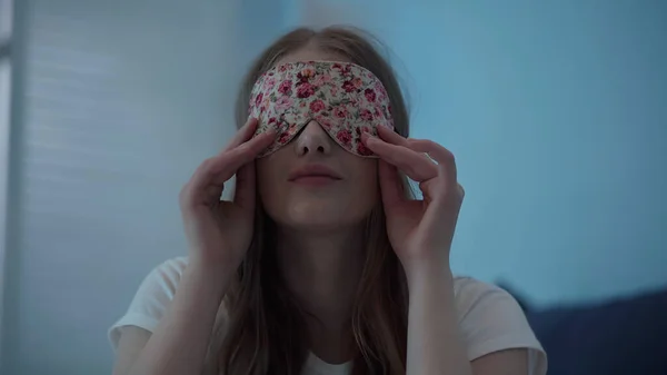 Young woman wearing sleep mask at home at night — стоковое фото