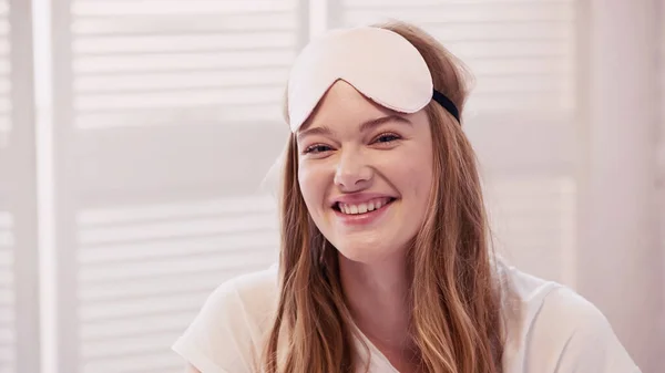 Happy young woman in sleep mask looking at camera at home — Stock Photo