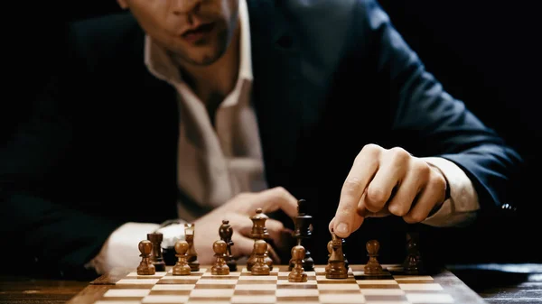 Cropped view of blurred businessman playing chess on table isolated on black — Foto stock