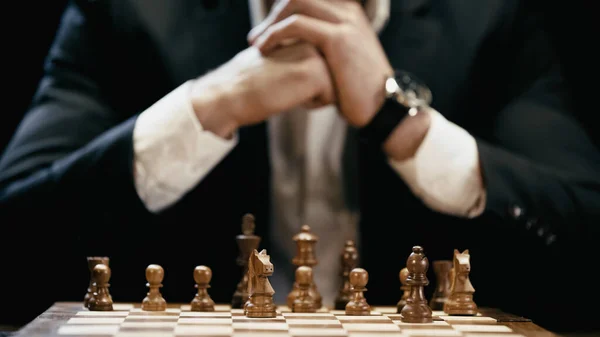 Cropped view of blurred businessman near chess board isolated on black — Photo de stock