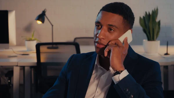 Африканский американский бизнесмен разговаривает на смартфоне в офисе ночью — стоковое фото