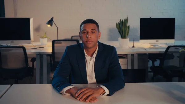 Afroamerikanischer Geschäftsmann im Anzug blickt im Büro in die Kamera — Stockfoto
