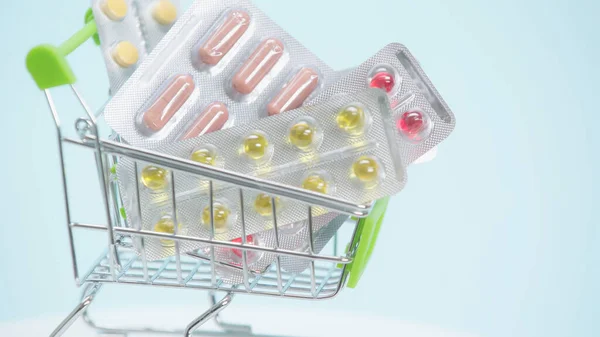 Vista de cerca de la pequeña cesta de la compra con pastillas sobre fondo azul — Stock Photo