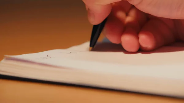 Vista cortada do homem segurando caneta enquanto escreve no bloco de notas — Fotografia de Stock
