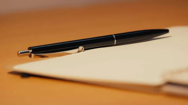 Close up vista da caneta perto notebook com folha em branco na mesa de madeira — Fotografia de Stock
