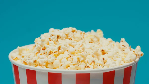 Delicious popcorn in big paper bucket isolated on blue — Stock Photo