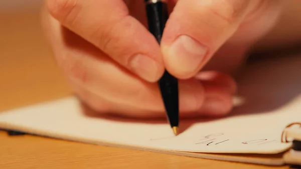 Vista de perto do homem segurando caneta enquanto escreve no caderno — Fotografia de Stock