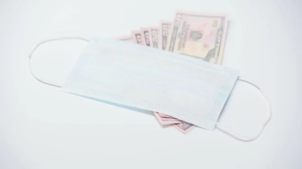 Захисна медична маска на доларових банкнотах на білому тлі — стокове фото