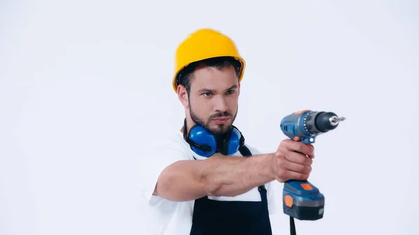 Seriöser Handwerker im Schutzhelm arbeitet mit Elektrobohrer isoliert auf weißem Untergrund — Stockfoto