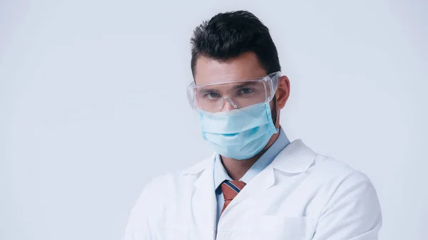 Brunette scientist in medical mask and goggles looking at camera isolated on grey — Stock Photo