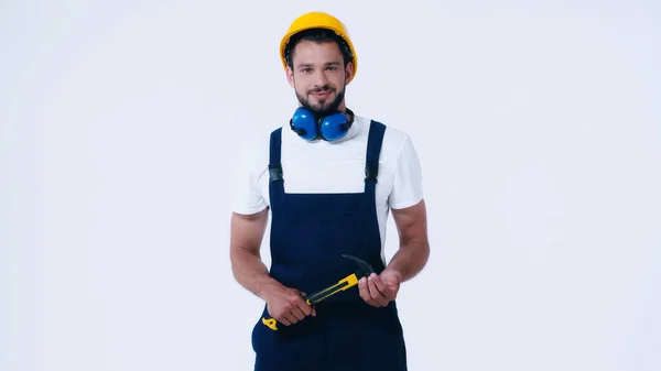 Jeune réparateur en salopette et équipement de protection tenant marteau isolé sur blanc — Photo de stock