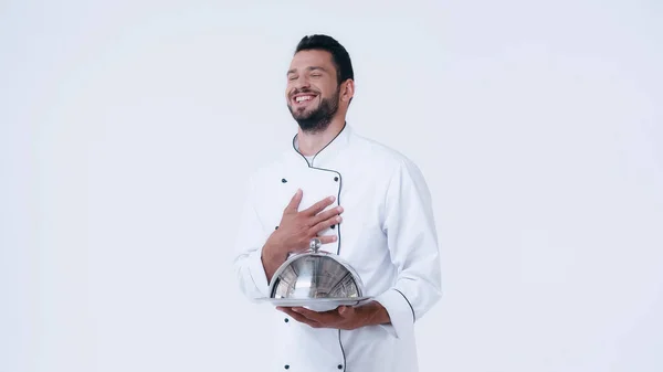 Кухар сміється з тарілкою і шафою, торкаючись грудей ізольовано на білому — стокове фото