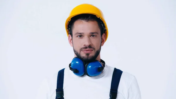 Young foreman with hardhat and ear protection headphones looking at camera isolated on white — Stock Photo