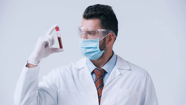 Brunette doctor in medical mask and latex glove holding test tube with blood isolated on grey — Stock Photo