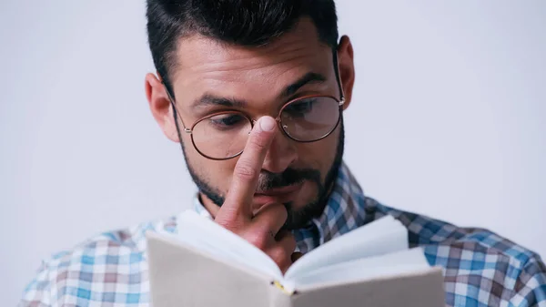 Nerd-Student justiert Brille beim Lesen verschwommenes Buch isoliert auf grau — Stockfoto