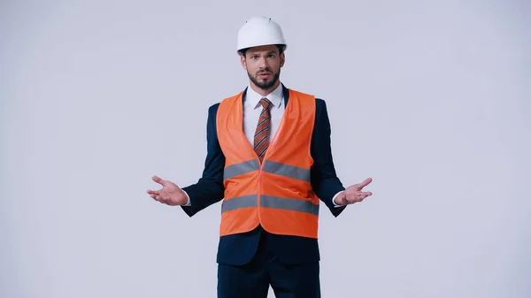 Confused foreman in formal wear and protective equipment showing shrug gesture isolated on grey — Stock Photo