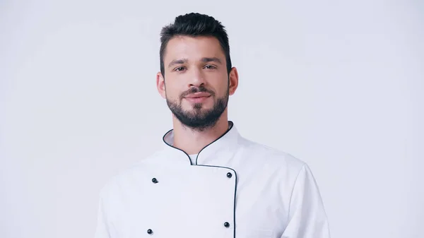 Позитивный бородатый шеф-повар в форме смотрит на камеру, изолированную на белом — стоковое фото