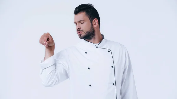 Barbudo hombre en chaqueta de chef condimento algo aislado en blanco - foto de stock