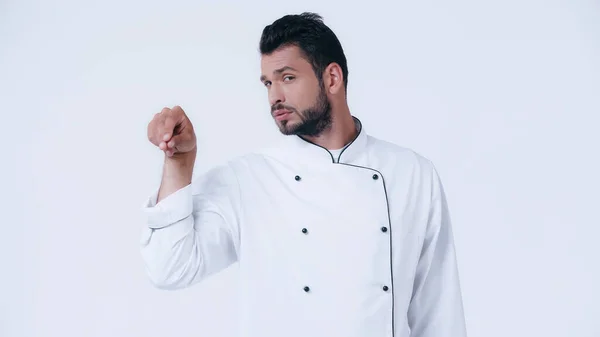 Junger Koch blickt in die Kamera, während er etwas Isoliertes auf Weiß würzt — Stockfoto