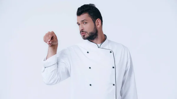 Young chef looking at camera while seasoning something isolated on white — Stock Photo