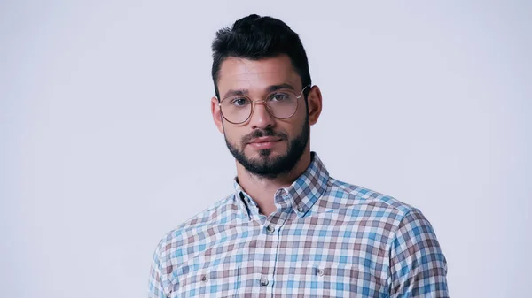 Jeune geek barbu dans des lunettes et chemise à carreaux regardant la caméra isolée sur gris — Photo de stock