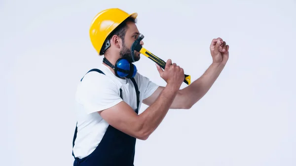 Vista laterale del tuttofare in hardhat che lavora con martello isolato su bianco — Foto stock