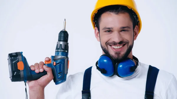 Jovem reparador com broca elétrica olhando para a câmera isolada no branco — Fotografia de Stock