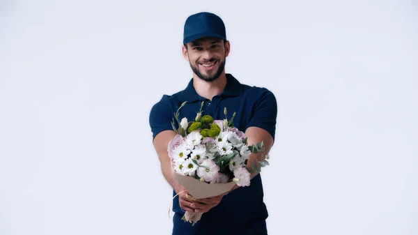 Hombre entrega feliz en uniforme azul sosteniendo flores aisladas en blanco - foto de stock