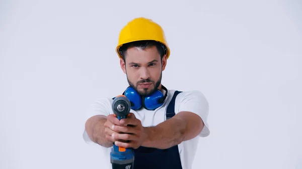 Riparatore in hardhat tenendo trapano elettrico e guardando la fotocamera isolata su bianco — Foto stock