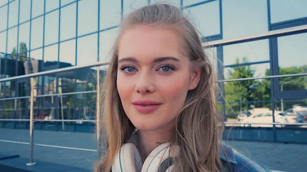 Young woman with headphones looking at camera outdoors — Stock Photo