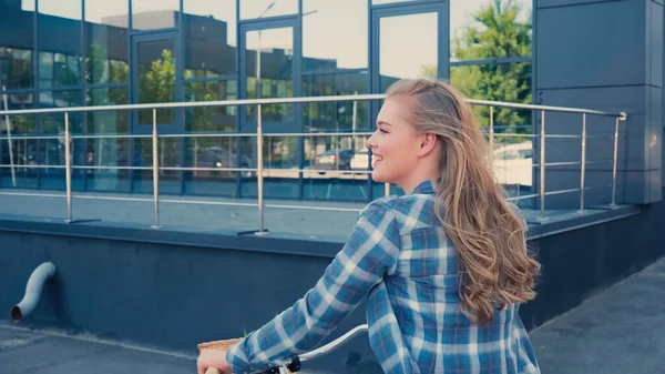 Vista laterale della donna allegra in bicicletta sulla strada urbana — Foto stock