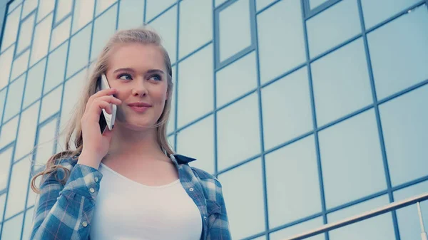 Tiefansicht einer lächelnden blonden Frau, die draußen auf dem Smartphone spricht — Stockfoto