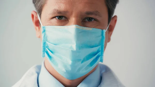Porträt eines Arztes mit medizinischer Maske, der isoliert auf graue Kamera blickt — Stockfoto