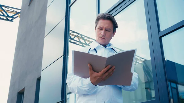 Low angle view of doctor with folder near city hospital outdoors — Stock Photo