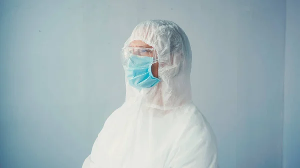 Doctor in hazmat suit and goggles with medical mask on grey background — Stock Photo