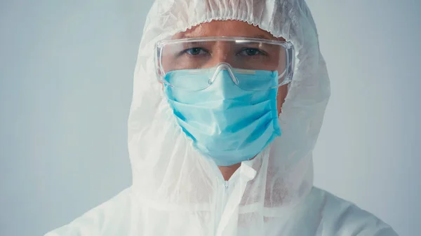 Portrait of scientist in hazmat suit and goggles with medical mask looking at camera isolated on grey — Stock Photo