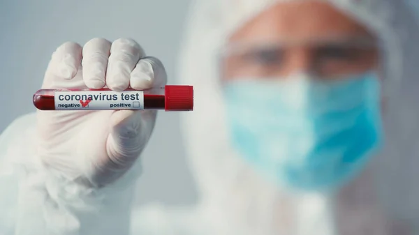 Selective focus of negative coronavirus test in hand of blurred virologist in latex glove isolated on grey — Stock Photo