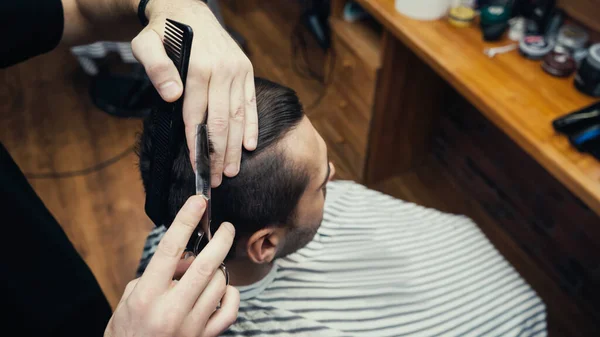 Високий кут зору перукаря, що ріже волосся клієнта в перукарні — стокове фото