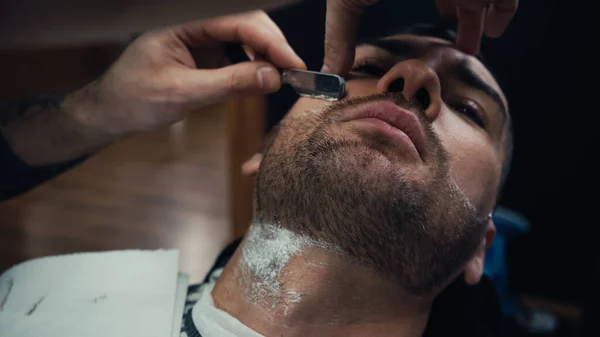 Barbero barba de afeitar del hombre con afeitadora y espuma en el salón - foto de stock