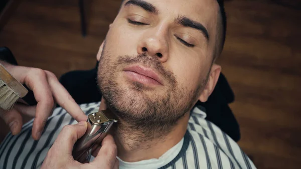 High angle view of barber trimming beard of man and holding brush in salon — Stock Photo