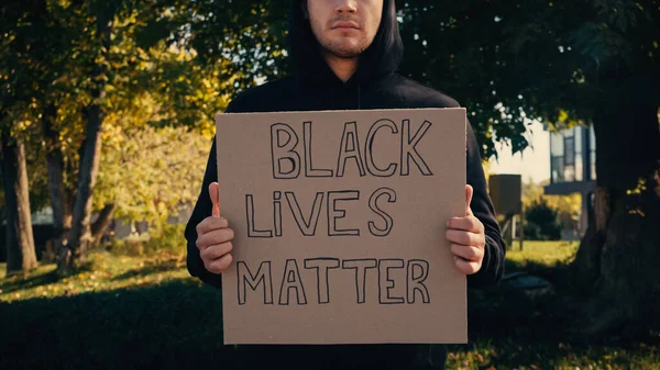 Vista cortada do homem segurando cartaz com vidas negras matéria lettering fora — Fotografia de Stock