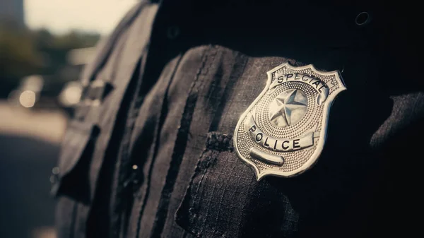 Lettrage spécial de la police sur l'insigne d'argent et uniforme noir du policier cultivé — Photo de stock