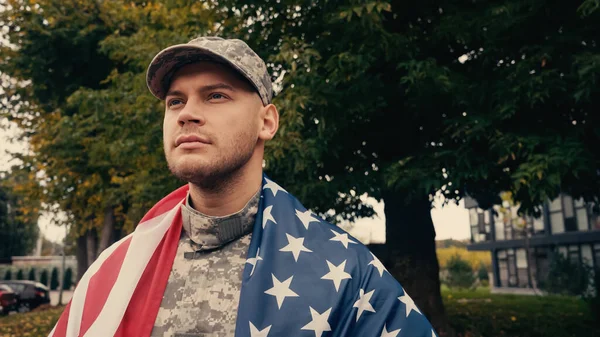 Stolzer Soldat mit amerikanischer Flagge, der in Militäruniform draußen steht — Stockfoto